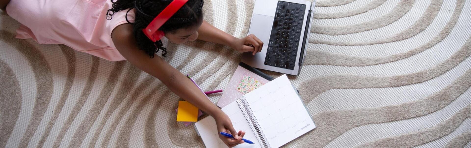 Student working with her laptop, wearing a red pair of headphones